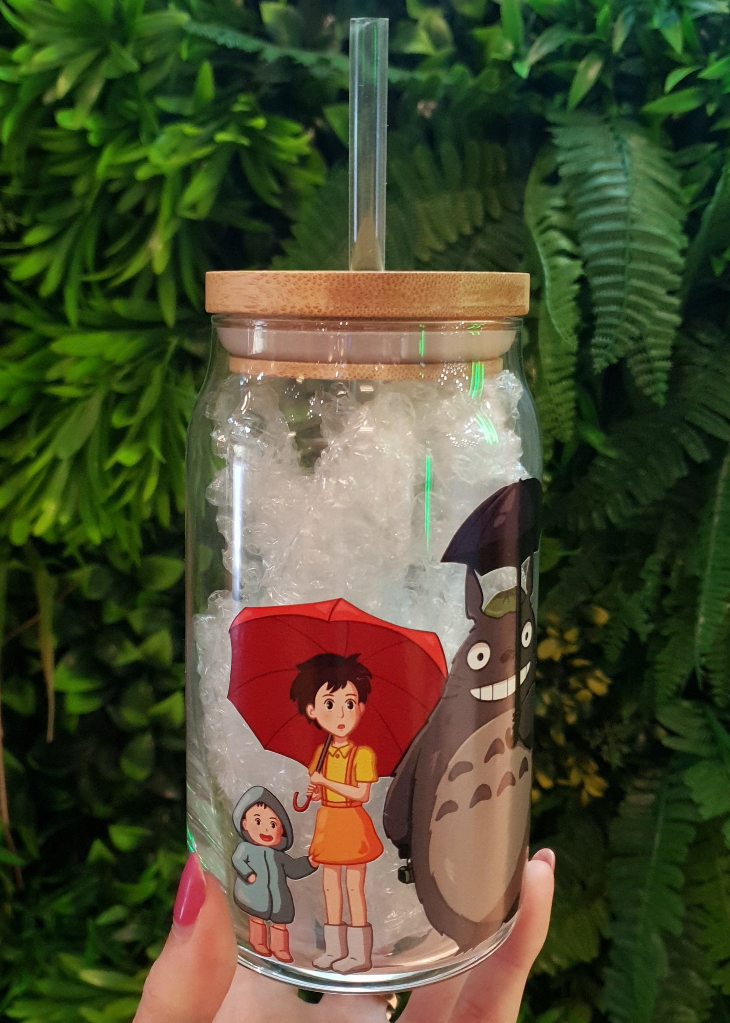 Tumbler with character design held against a green leafy background