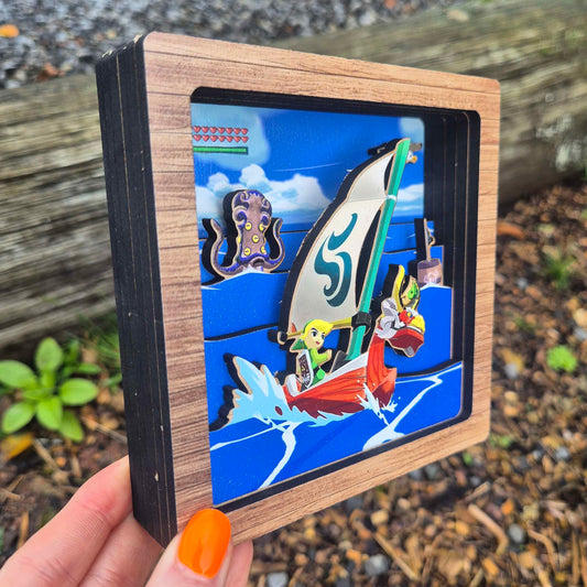 Hand holding a small wooden box with a colorful illustration of cartoon characters on a beach.