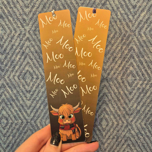 Two brown bookmarks with a cow illustration and 'Moo' text held against a patterned background.